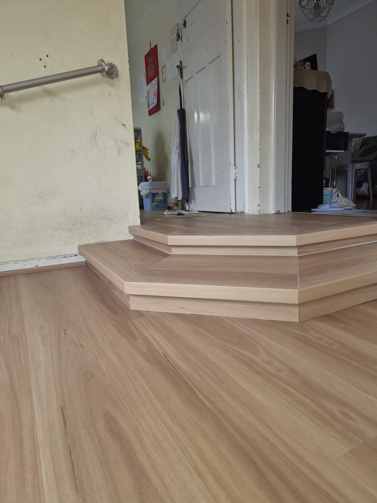 Completed interior modification featuring R10 hybrid timber-look flooring, custom rebuilt two-step transition, and stainless steel wall grab rail.