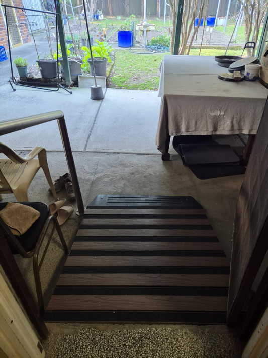 Access ramp with non-slip safety tapes installed at doorway leading to outdoor covered patio.